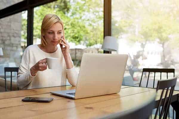 Guide to insurance for management consultants - management consultant in cafe working from laptop and speaking on the phone