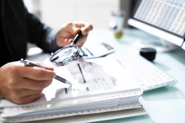 A small business owner reading a tax return with a magnifying glass.