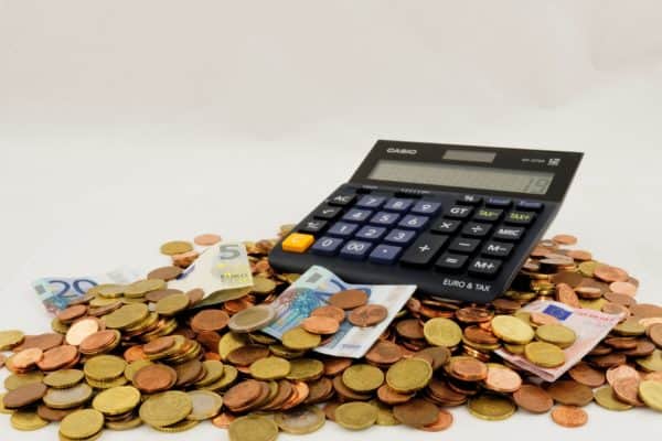A calculator and a pile of money you'll save for your vacation by cutting the trip's expenses.