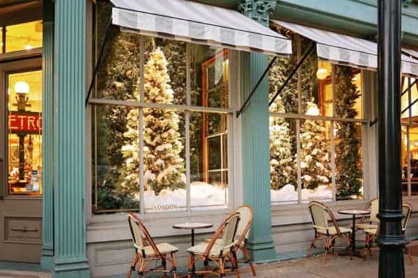 The elegant christmas windows at savannah's paris market shop with bistro tables outside.