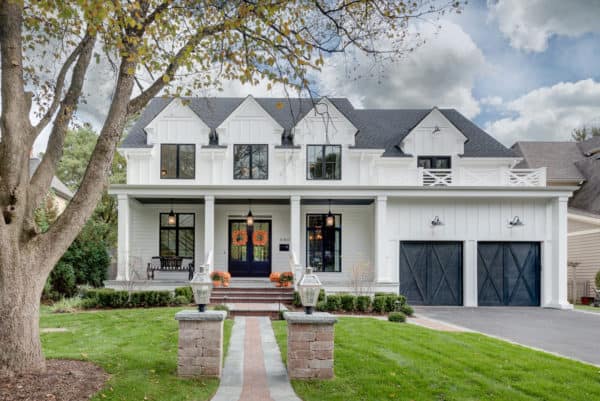 classic farmhouse with black crossbuck garage doors in traditional barn style