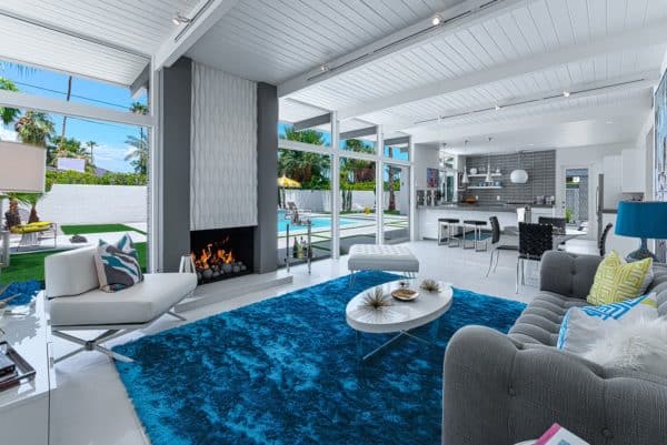 open concept living space with white floors and ceilings, gray walls, and doors that open to the backyard