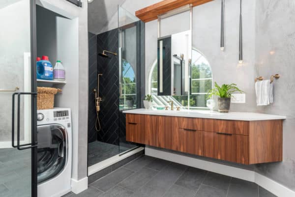 black tiled shower and hidden washing machine for an exquisite bathroom and laundry room combo