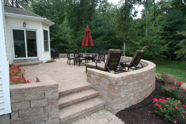 blend your raised patio against the house with a retaining wall frame and plantings