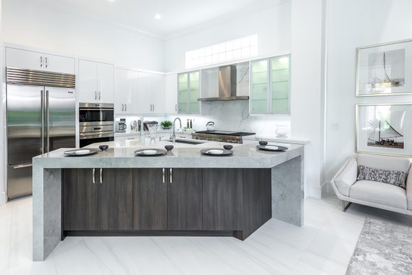 modern kitchen with an asymmetric island bar looks expensive with white tile floors