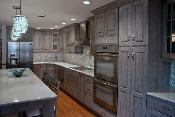 a gorgeous all-grey kitchen with grey cabinets, mosaic backsplash, and medium toned wood floor