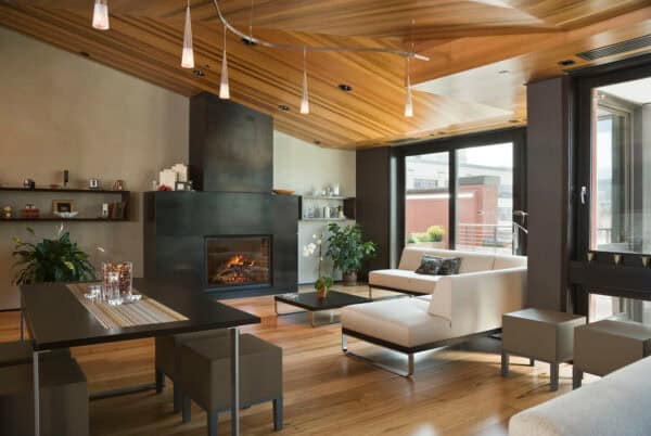 this chic and modern living room features a wood ceiling with track lighting and floating shelves next to the fireplace for convenient storage