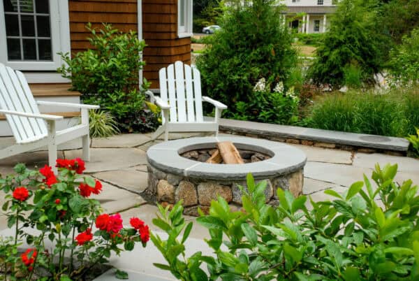 white adirondack chairs look stylish on an irregular bluestone patio with a round open fire pit