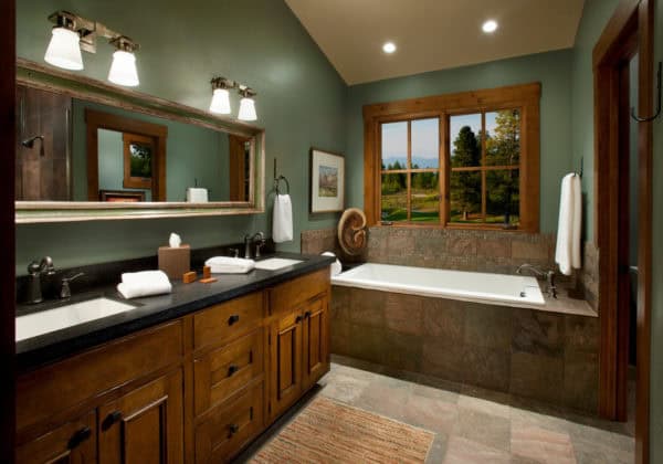 evoke rustic vibes in this mountain style bathroom featuring green walls and brown furniture