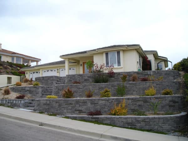 multi-tiered front yard retaining wall with gorgeous perennials to create a grand house design