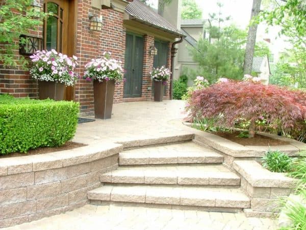 induce old-school charm in a red brick home with stone front yard retaining wall and huge vases