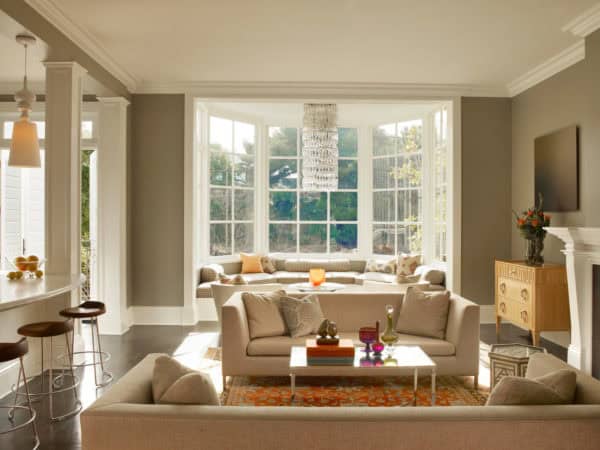 a beautiful bay window design in an eclectic living room with brown walls and a contemporary chandelier