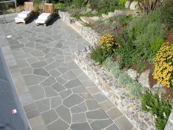 combine irregular bluestone patio with lush landscaping for an elegant pool deck