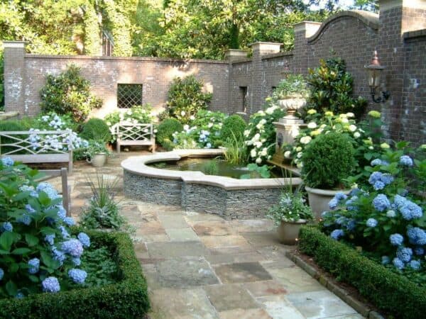 this backyard wall uses slate-colored bricks from england and a variety of greeneries to create a secret garden atmosphere