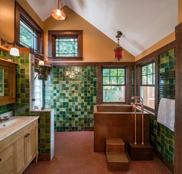 a dark and cozy craftsman bathroom pairs brown walls with multi-shaded green mosaic tiles