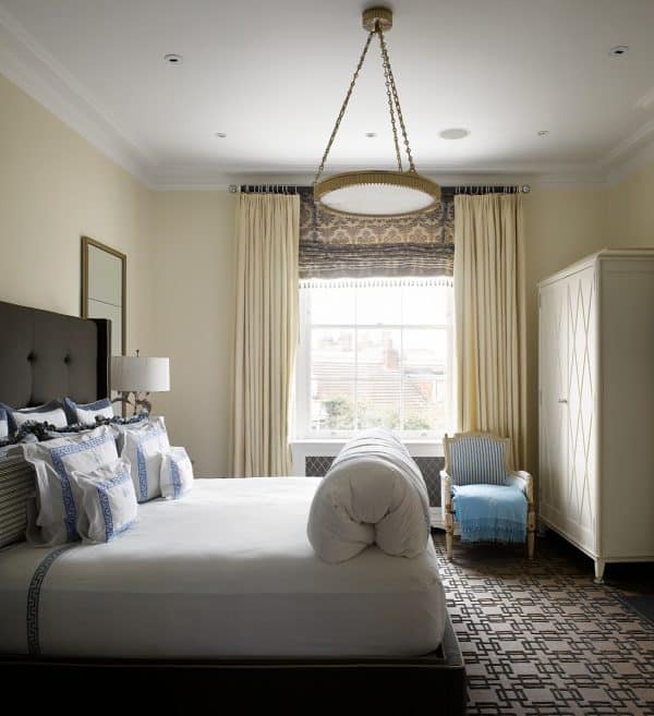 this bedroom features brown roman shades with beige curtains in a soothing yellow and brown color scheme