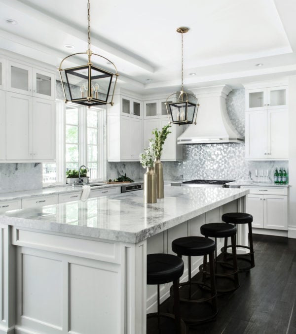 sophisticated white kitchen bursting with grand marble surfaces and stainless appliances