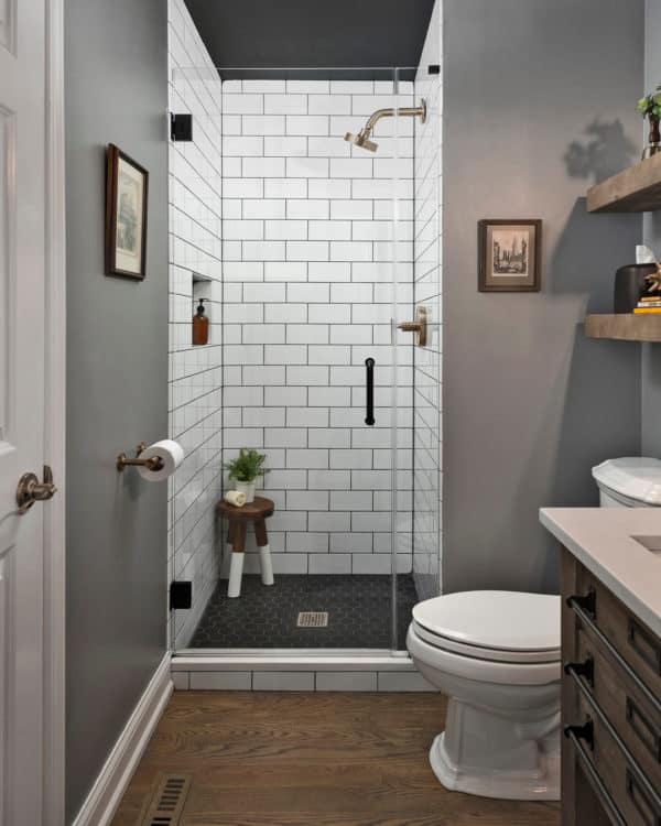 wood flooring and grey walls to contrast subway tile with black grout in a cozy bathroom