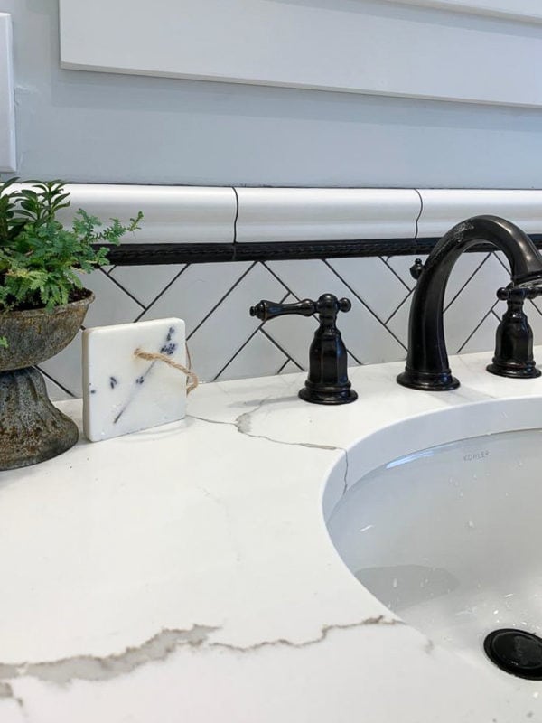 subway tile with black grout makes a dynamic bathroom backsplash against black faucets