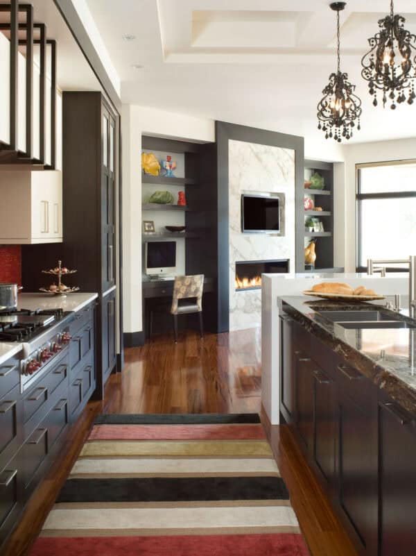 this open-concept kitchen and living room feature floating shelves next to the fireplace and a built-in desk for the ultimate functionality