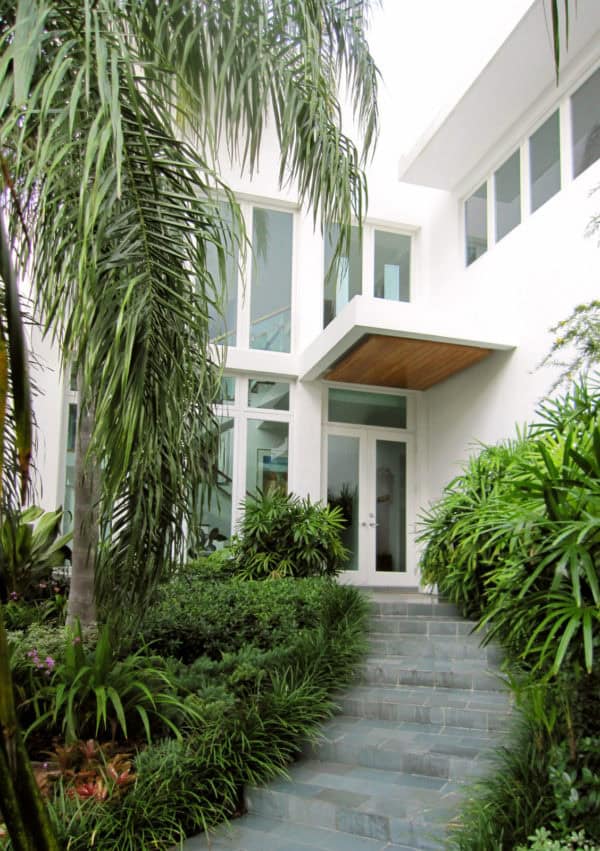 embrace the minimalist style with a wooden roof over door entry in a contemporary white home exterior