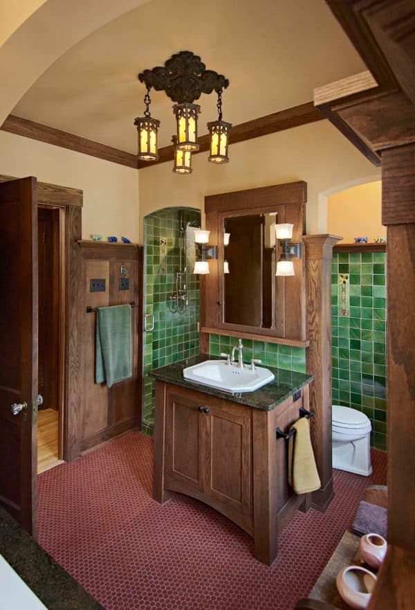 a craftsman inspired master bathroom with green mosaic walls and antique brown cabinets