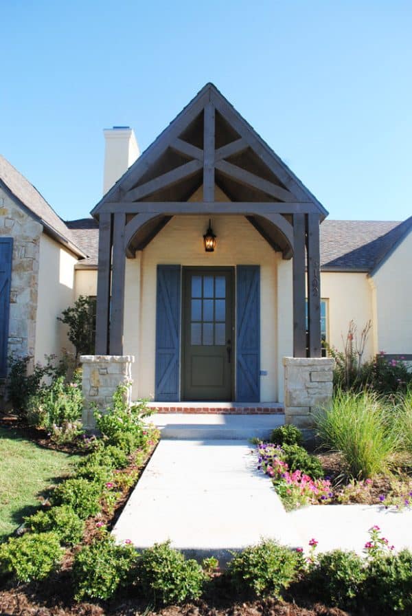 use stained wood portico to enhance your yellow house with blue wooden shutters