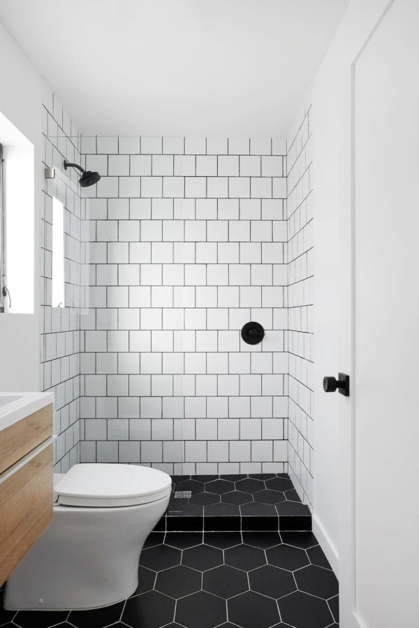 pair subway tile with black grout walls and black honeycomb tile floors for a modern bathroom