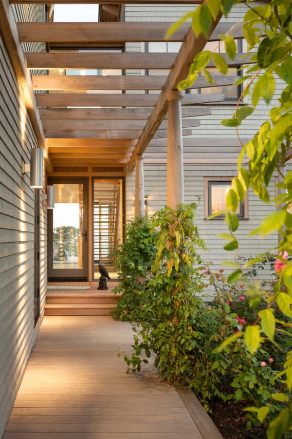 a simple wooden pergola complements the elegant light wood flooring and glass front door