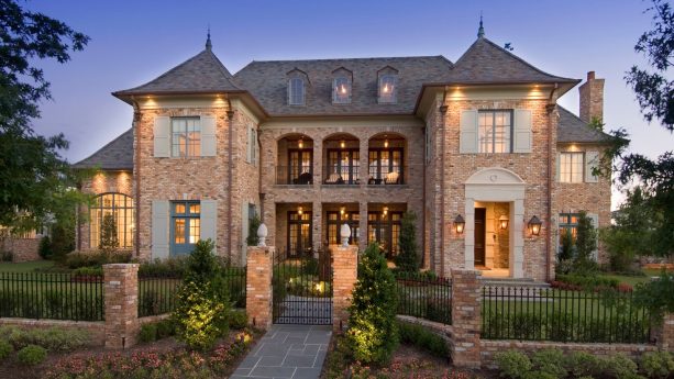 french country brick house with shutters in a combination of light gray green color