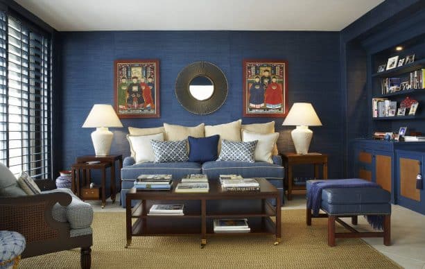 living room with navy blue grasscloth walls, navy blue cabinets, soft blue sofa, beige cushions, and beige flooring