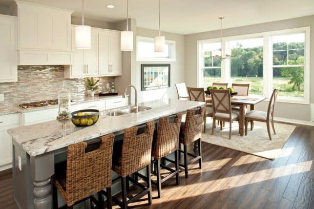 open transitional kitchen and dining room with light and warm grey walls and dark color hickory wood floor