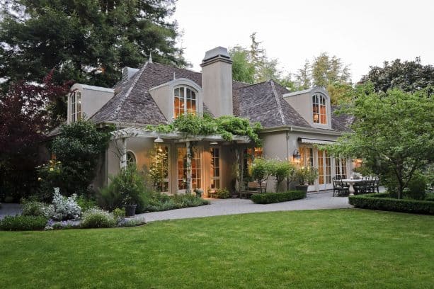 a French country exterior with tan stucco and off-white trim