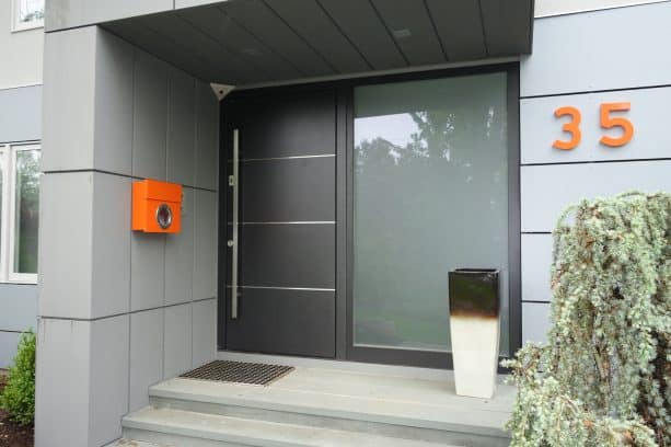 a dark grey front door in a metallic finish and a limestone floor enhance the look of a modern home entryway