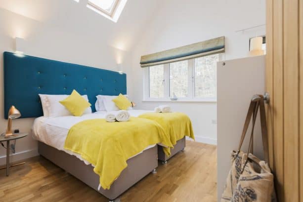 a bedroom with teal headboards and mustard pillows and blankets