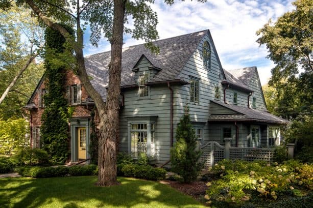 a sage green traditional exterior with grey roof shingles