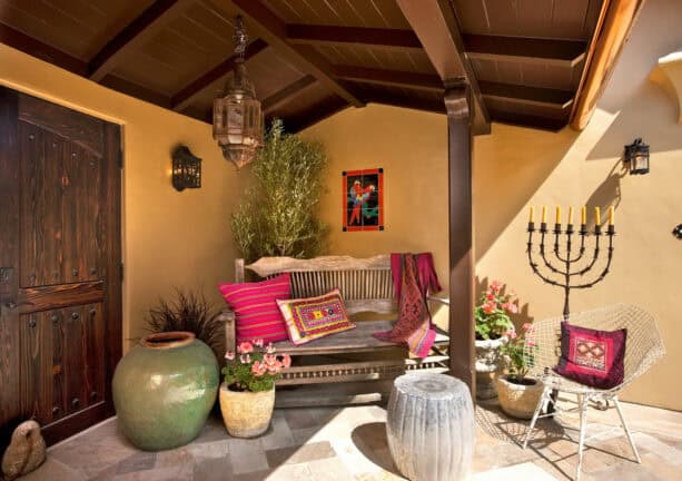 simple wooden bench and a chair accentuated by bright pillows as a front porch seating