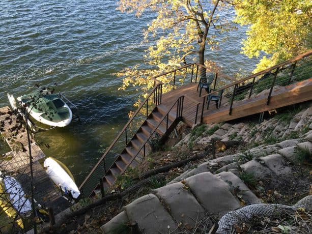 a metal, cable, and wood railing combination of a contemporary stairway that leads to a boat docking