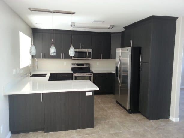 polished and sleek kitchen with dark gray cabinets and beige floor