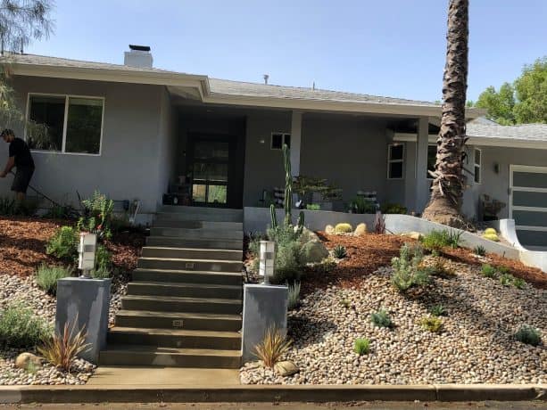 sloped grassless front yard garden filled with mulch, river pebbles, and boulders