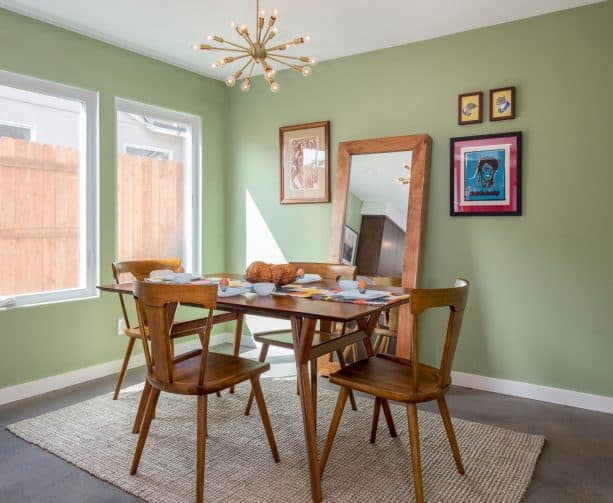 the combination of sage green walls and wooden furniture in a midcentury dining room