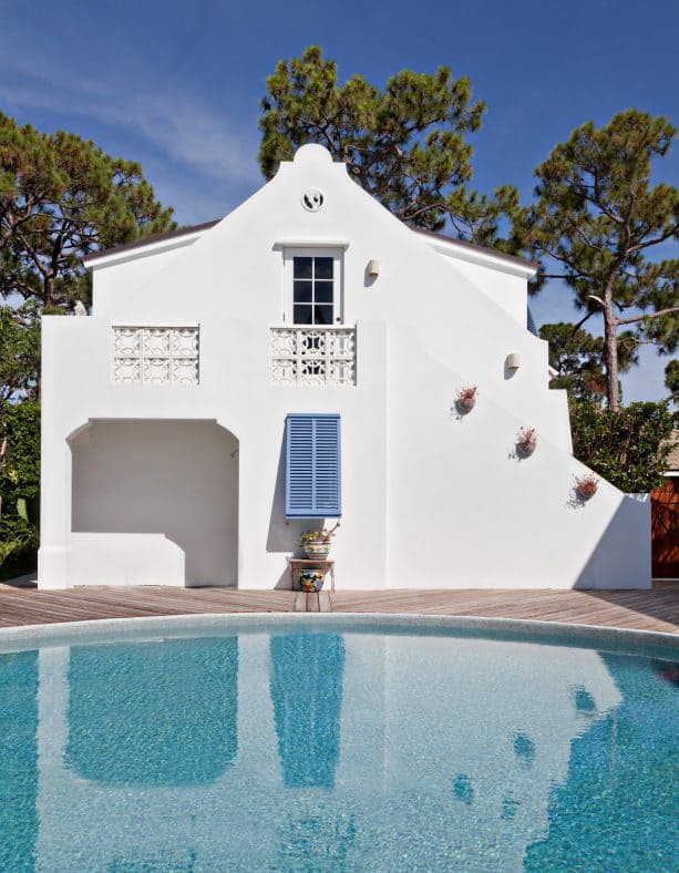 two-story tropical house in white with a decorative blue shutter installation