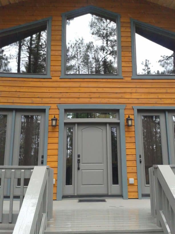 an appealing rustic look is an easy target to achieve when one has a grey front door and bright brown wooden walls plus a light wood floor entryway