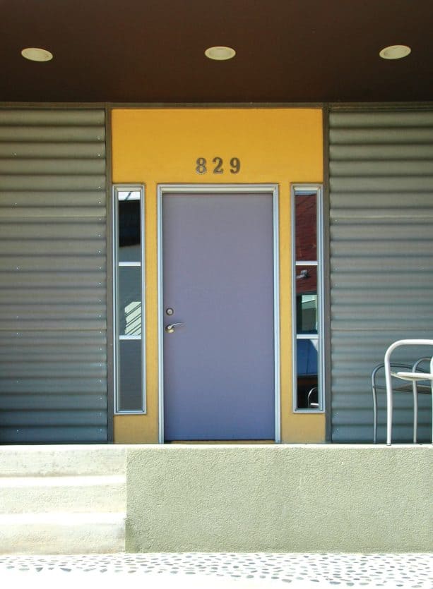 a pretty pop is something that a grey front door on a yellow wall with unique small windows never fails to add to a courtyard duplex