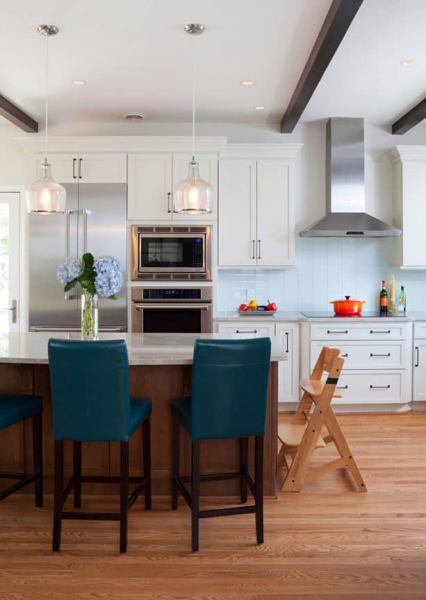 a kitchen with white cabinets and teal armless stools