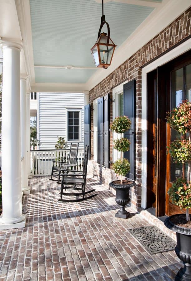 elegant porch of a brick house with charleston green shutters