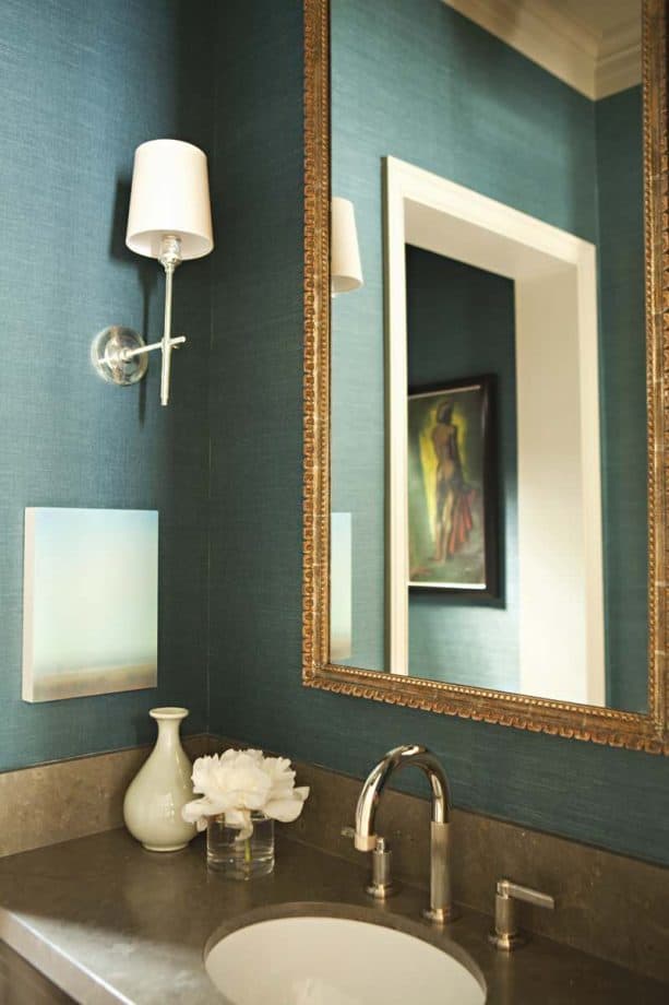 a bathroom with golden mirror that go with muted teal grasscloth wall