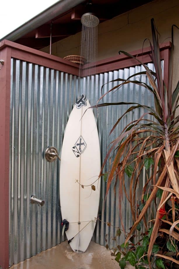 an outdoor shower with corrugated metal fencing as the walls