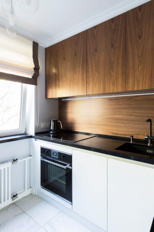 a contrast look from medium tone wood kitchen backsplash and glossy black countertops