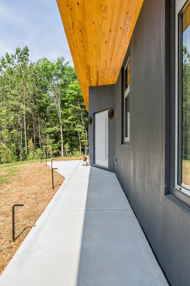 a light grey front door that contrasts against a wall in a darker shade of the color, and a bright wooden ceiling can never make an entryway look bad